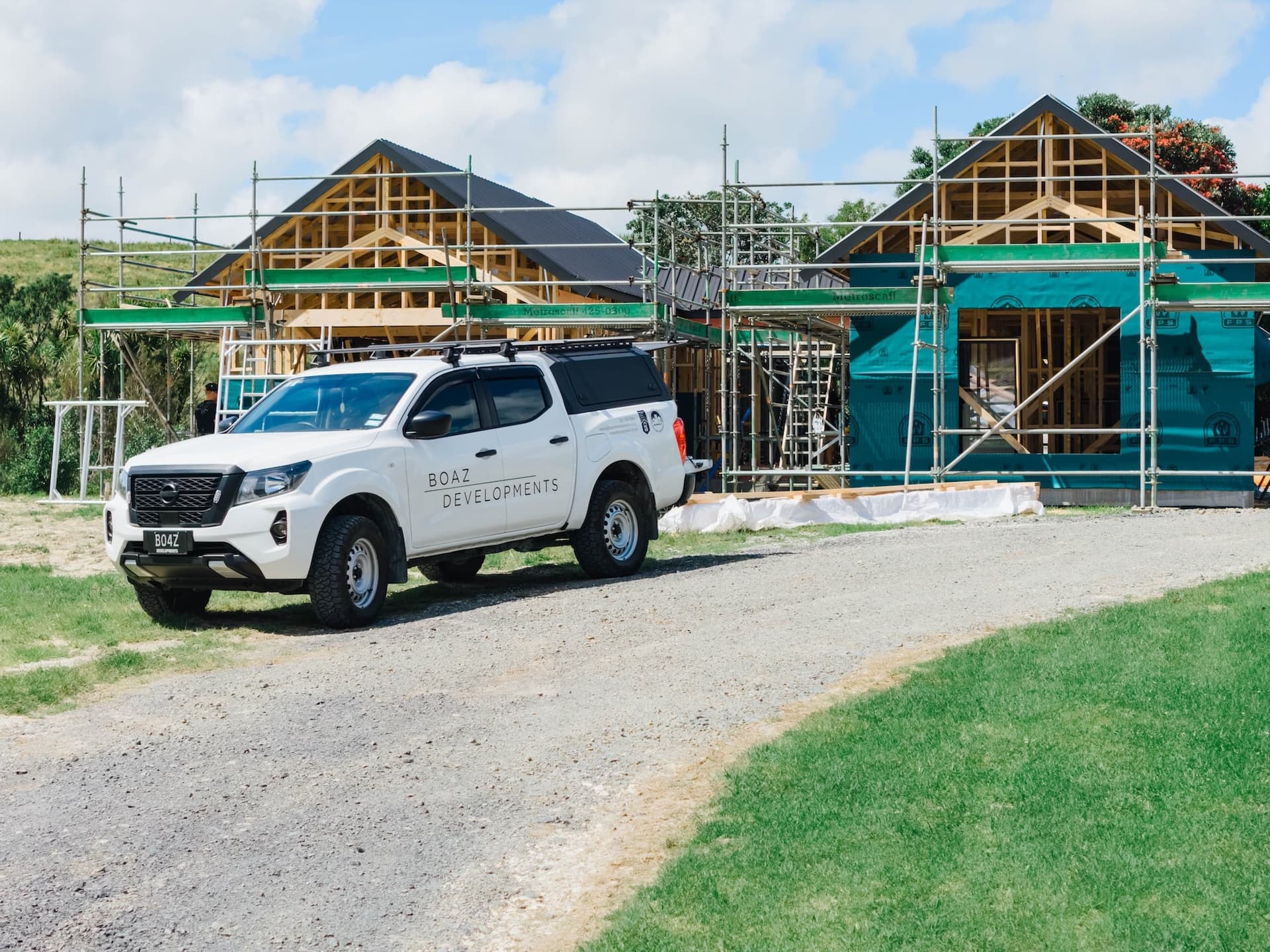 Boaz Developments ute on-site at a Mangawhai family home build, two gable structures under scaffolding